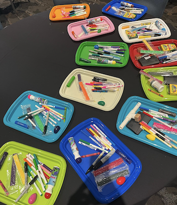 Art materials in trays ready to be used by the 75 plus participants who attended our presentation
