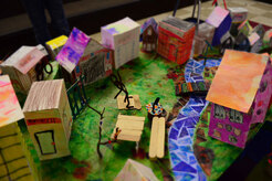 Village of the future built by students during an arts integrated residency. Buildings are constructed from card, paint and paper mosaic