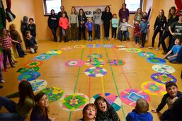 Students stand around a series of circular mandalas on the ground constructed from colored rice